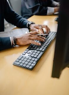 Close-up of hands typing on keyboard in an office setting, showcasing work professionalism.